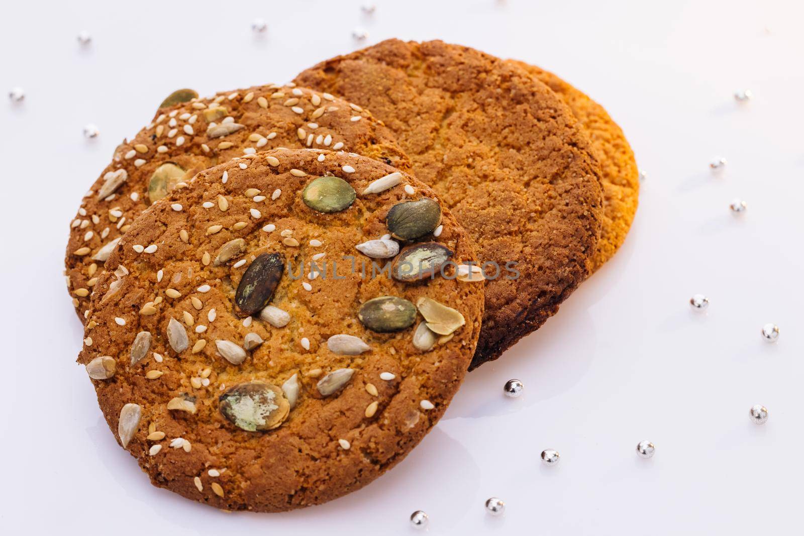 Wheat fall on dietary cookies. Eat oatmeal cookies. Oatmeal cookie on the table with sesame seeds on white background. The concept of making chip cookies by uflypro