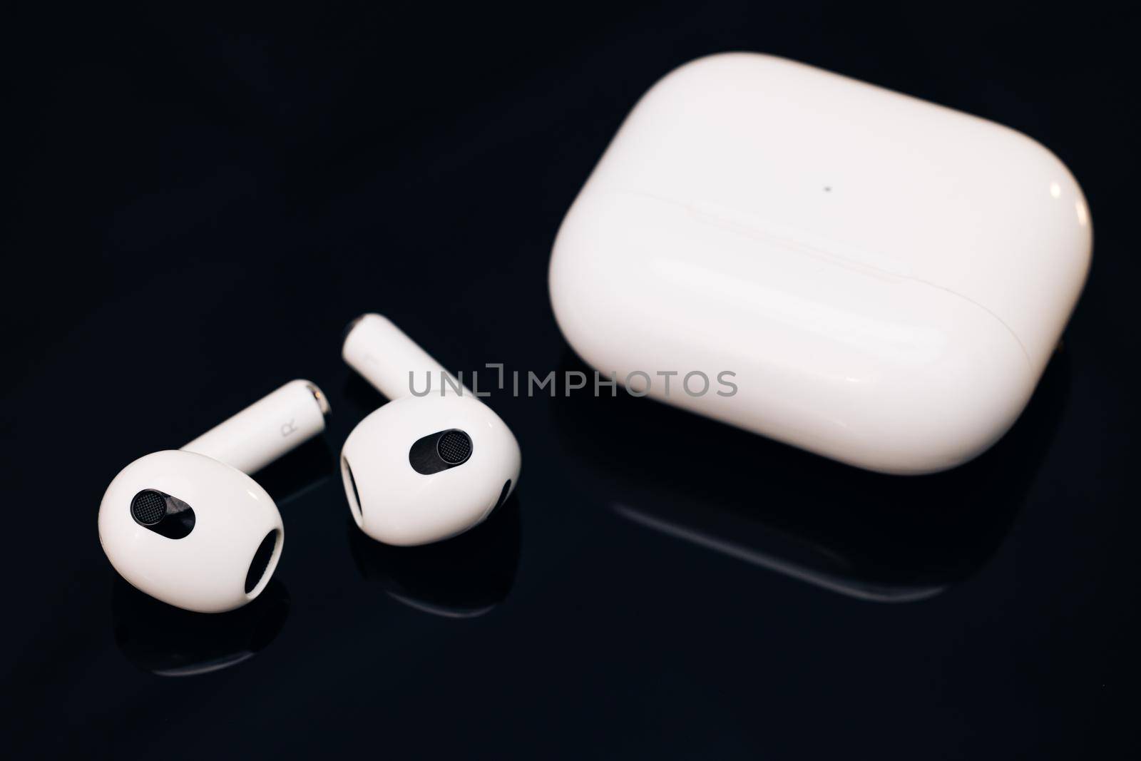 Wireless earphone with noise cancelling technology on black background. Wireless headphones with charging case.