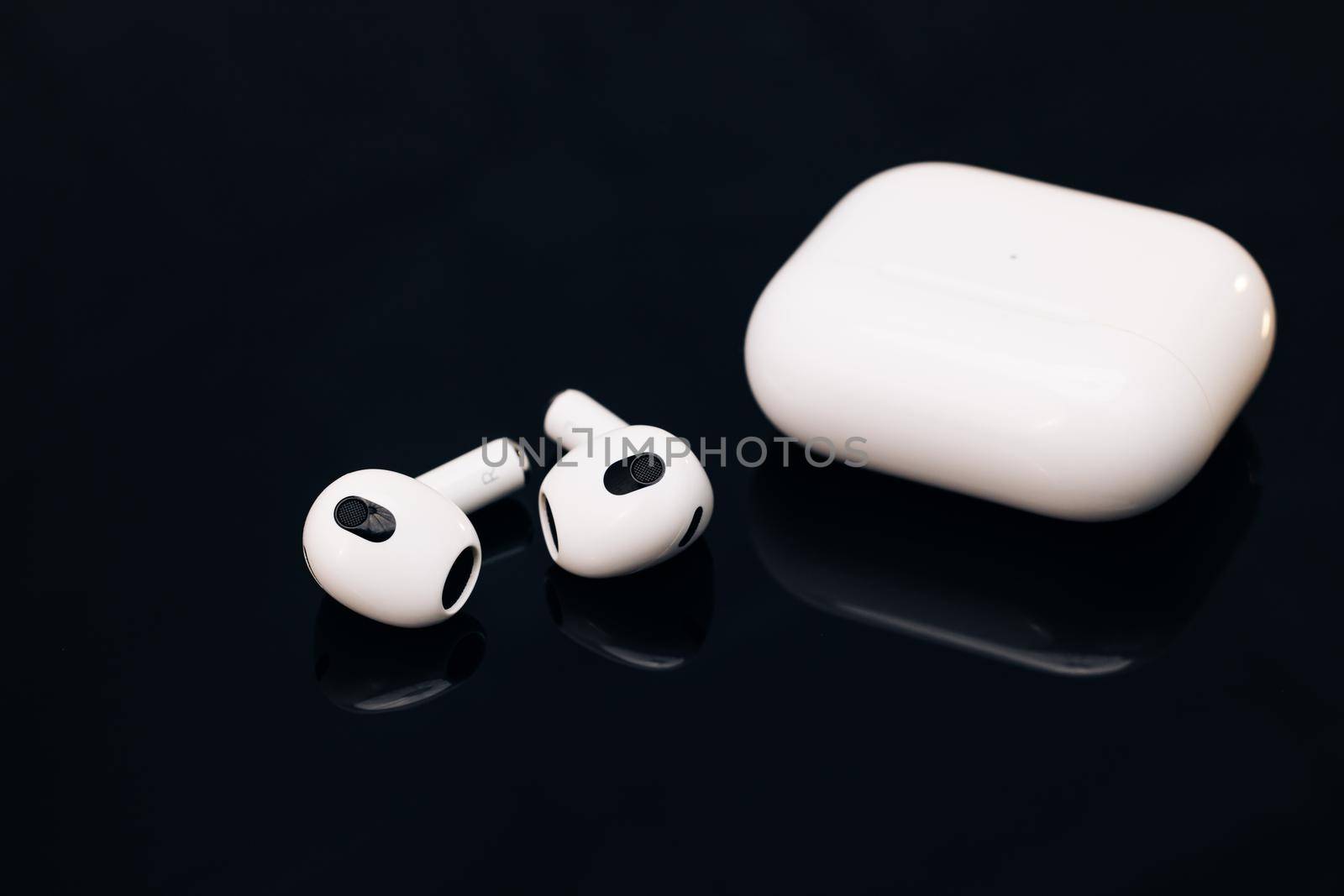 Wireless earphone with noise cancelling technology. Bluetooth headphones isolated on black background. Wireless headphones with charging case. Gadgets and electronic devices. by uflypro