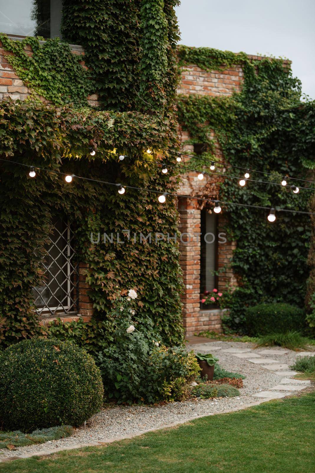 villa red brick restaurant overgrown with green wild grapes