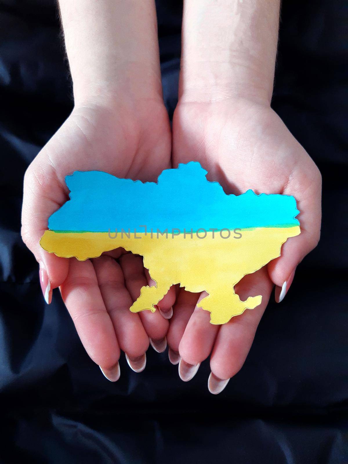 Map of Ukraine in the color of the Ukrainian flag on the palms of a girl.