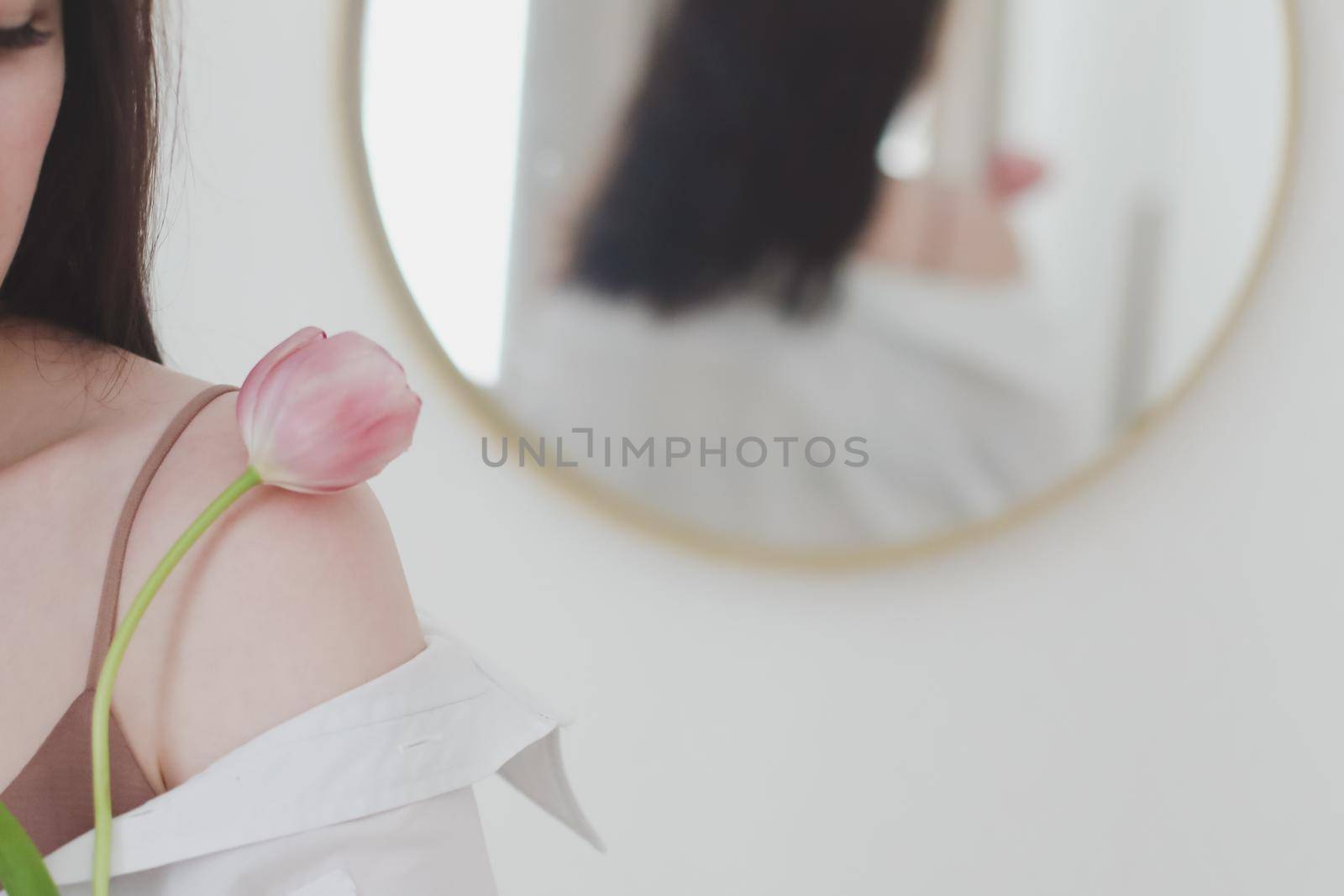 spring portrait of a young woman with pink fresh tulip on white background.