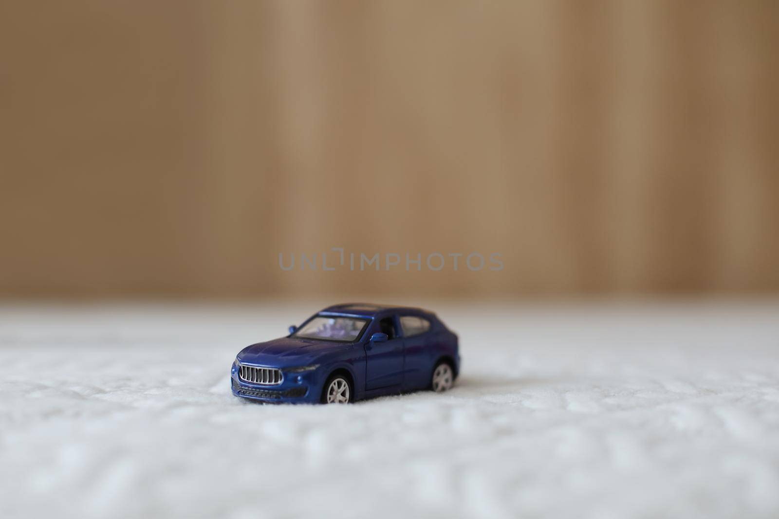 Miniature blue plastic toy car on textile material macro shot. close-up.