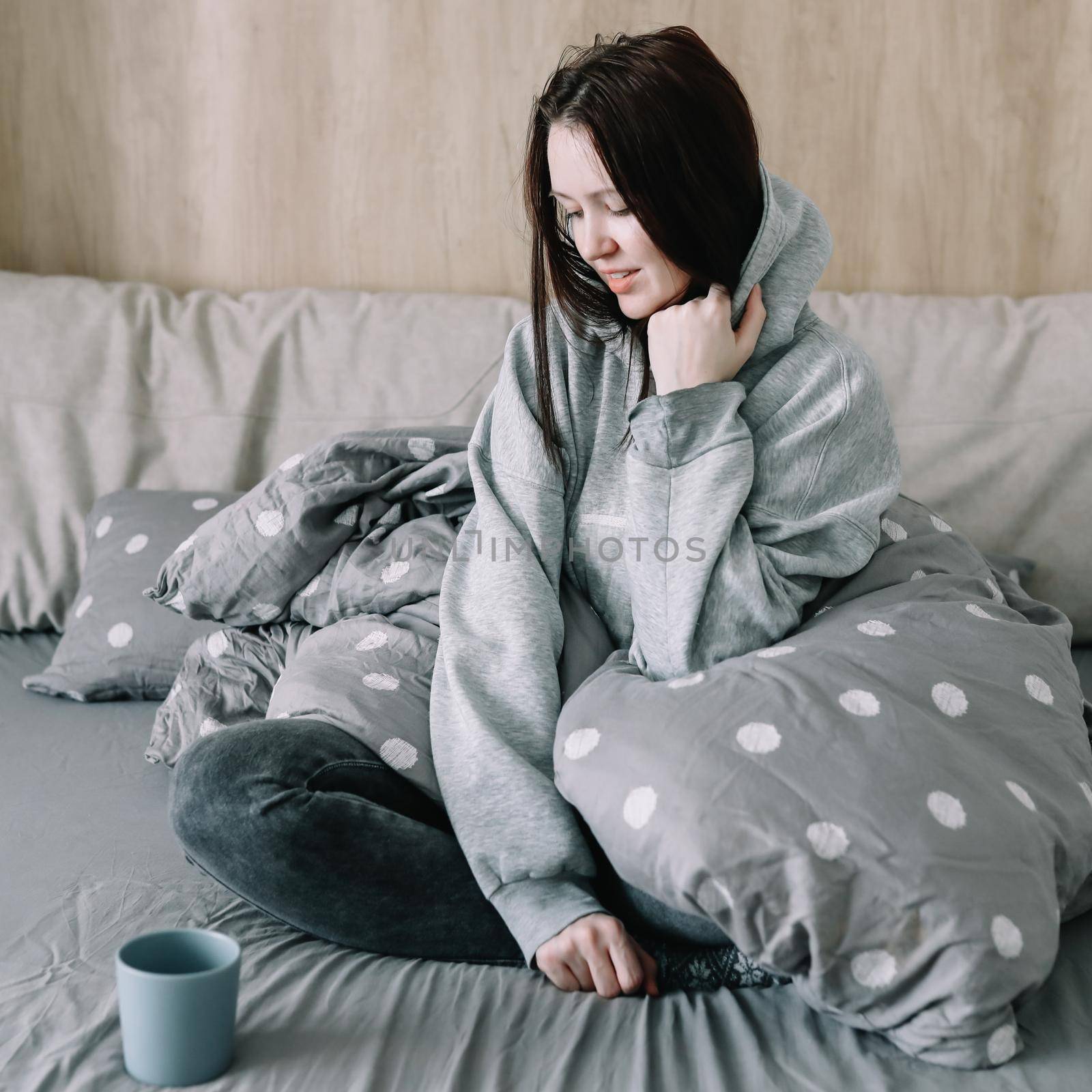 Woman get up and drinking coffee in a cozy bed room at home, early out morning and wake up rest sunny day. Morning quiet time. A young woman enjoing in bed, lazy day, cozy home atmosphere.