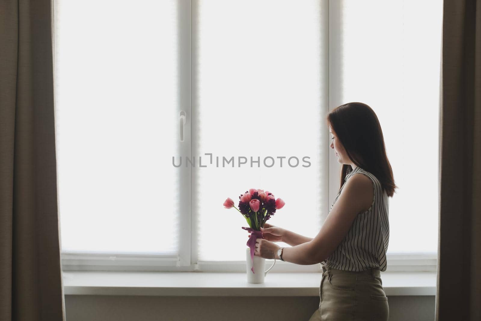 young woman with a pink tulip bouquet at home. Spring stll life, birthday, Easter concept.