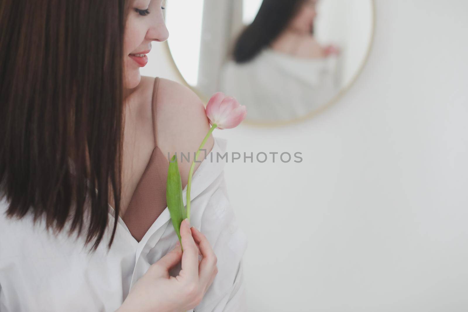 spring portrait of a young woman with pink fresh tulip on white background.