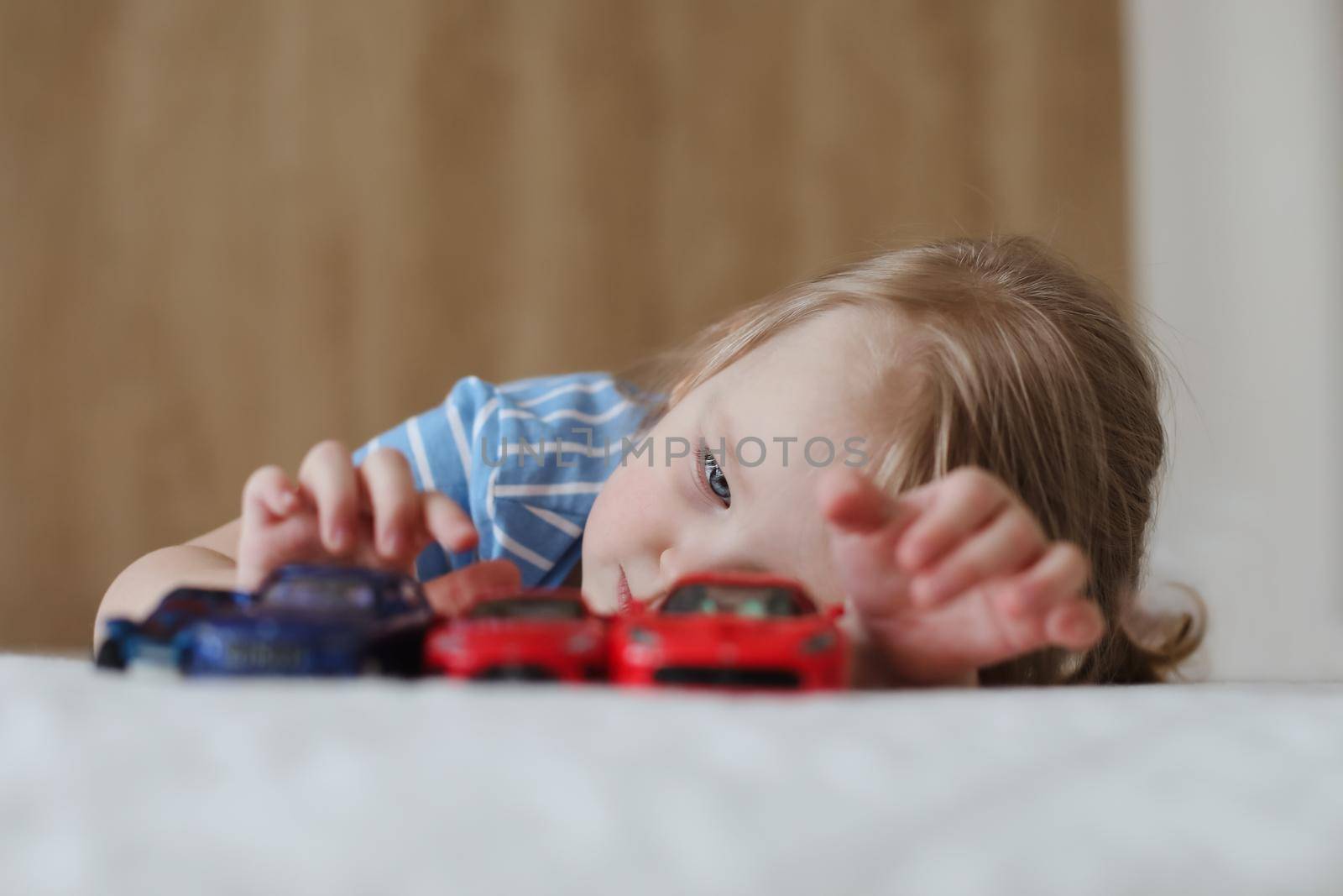 Portrait of child playing with toy cars indoors. Toddler having fun.