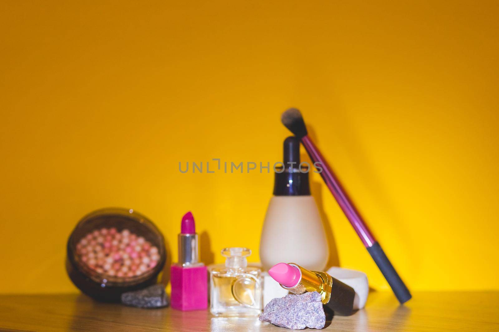 Set of cosmetic products lipsticks, powder, makeup brushes on pink background. Beauty products for professional fashionable makeup