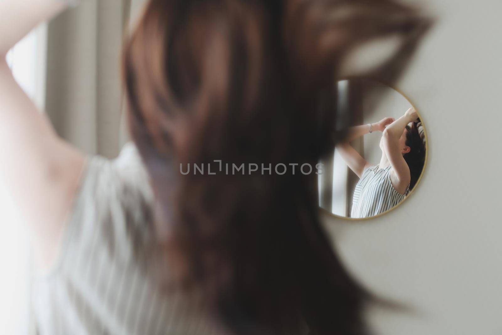 portrait of the young woman looking in the mirror at her hair. 