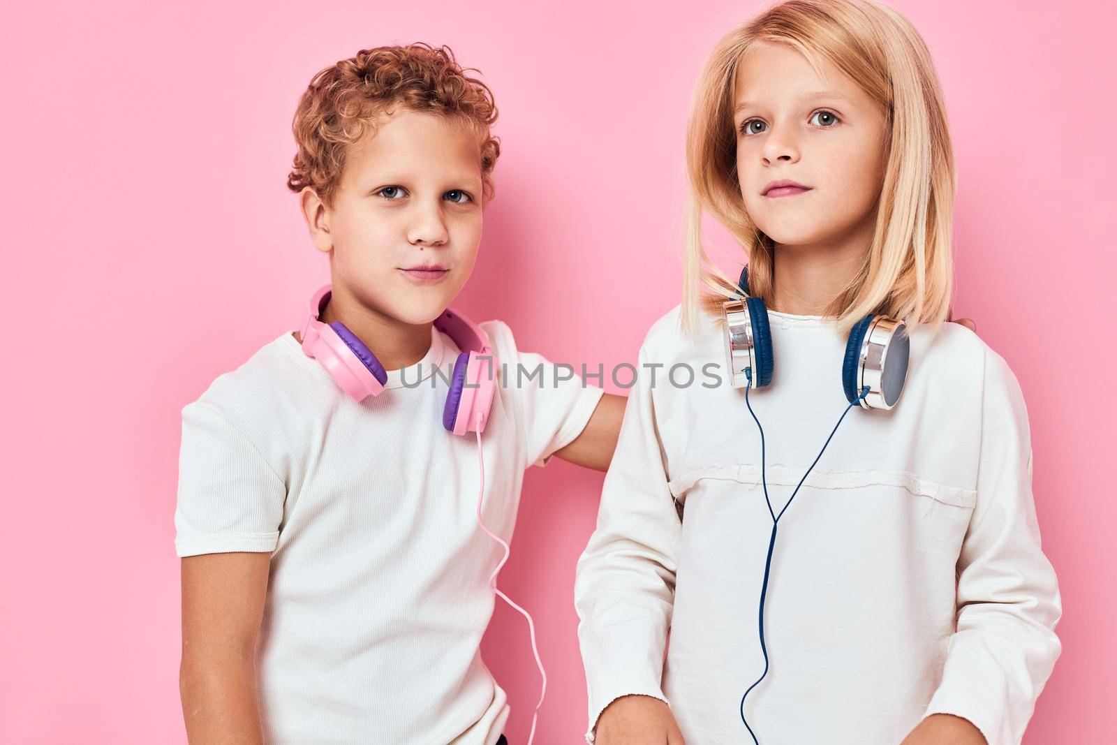 Active young people stand next to in headphones pink color background. High quality photo