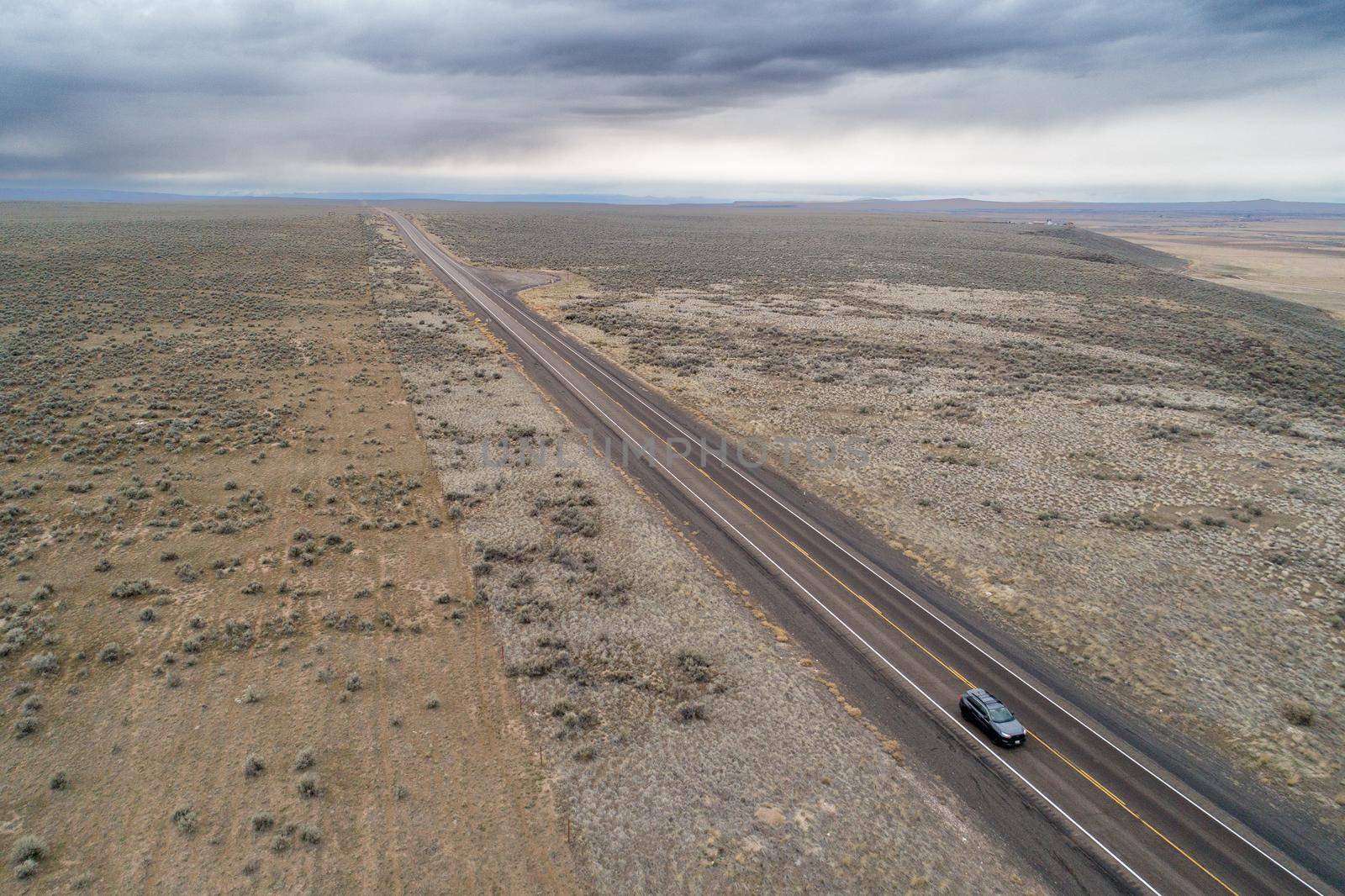 Aerial view of a car driving through a deserted area in the middle of nowhere