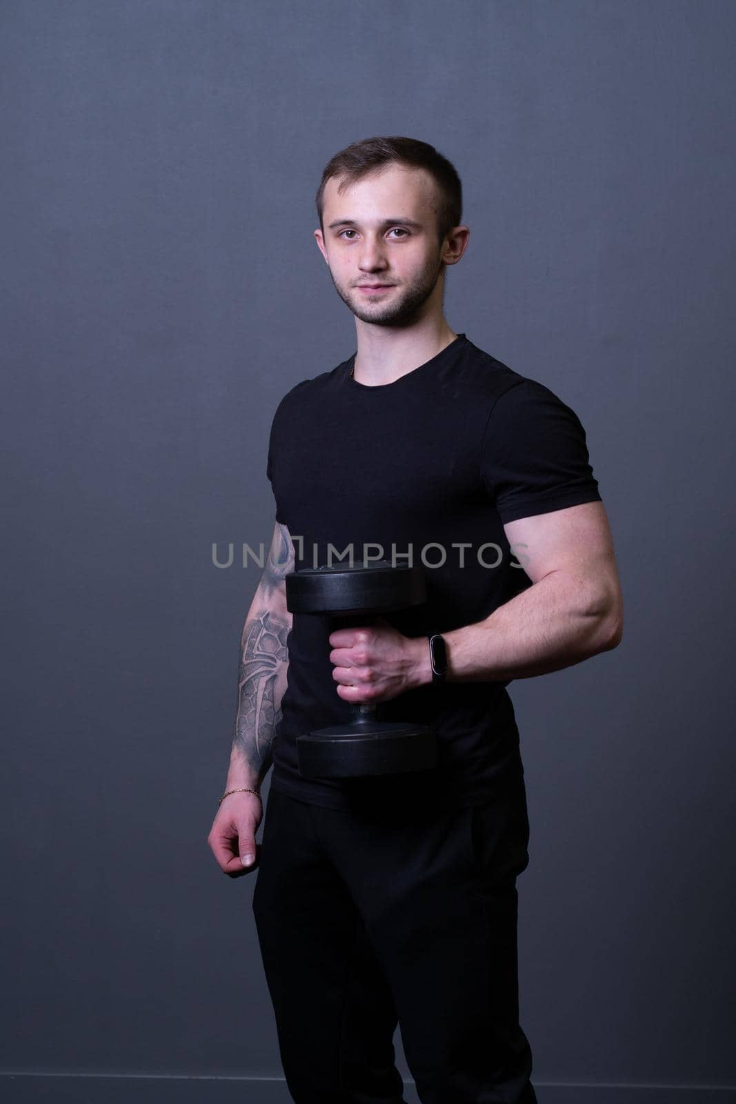 A guy with dumbbells in a black T-shirt muscular man sport posing, from aged dumbbells for male from body athletic, adult muscle. Active bodybuilder exercise, gym young