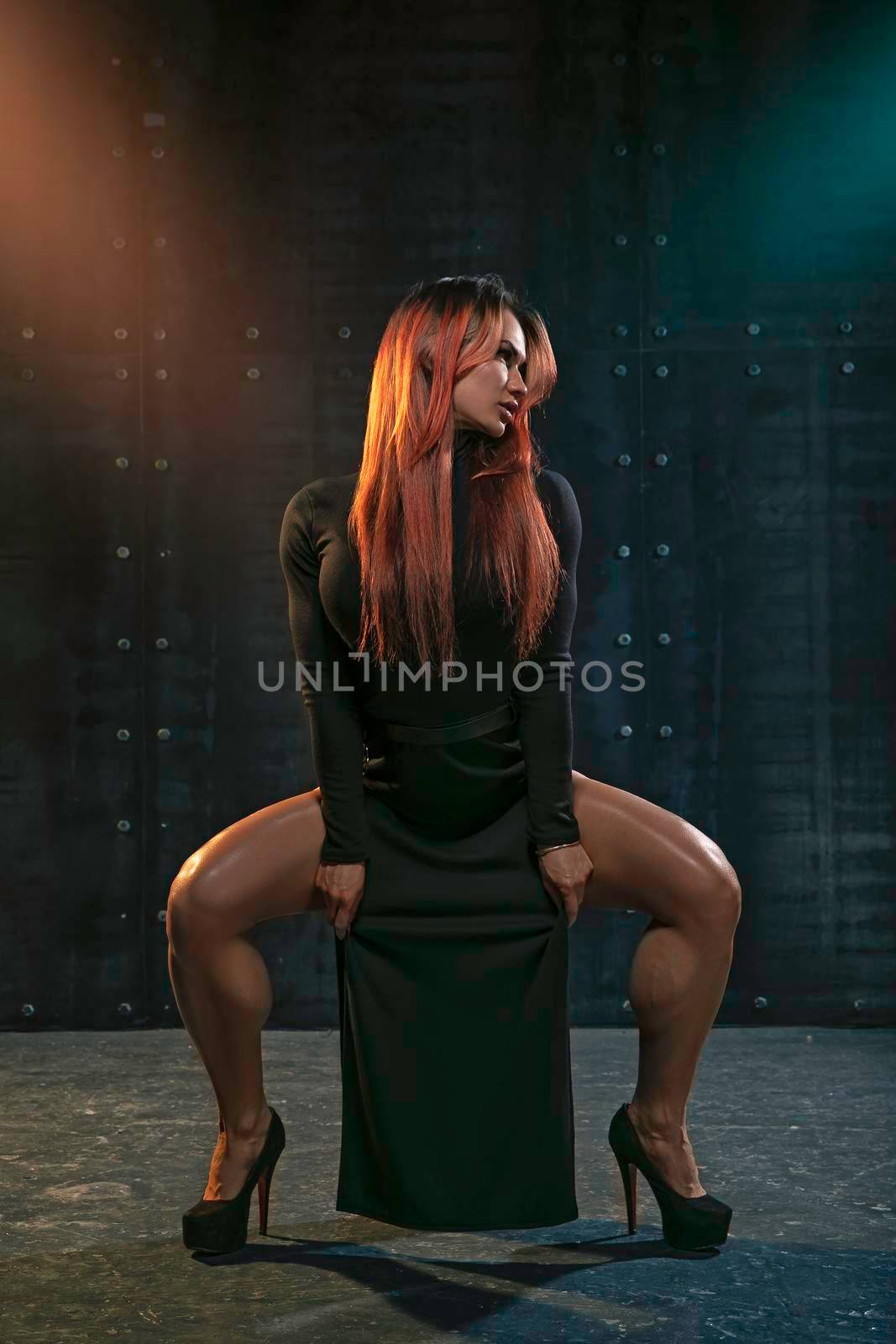 Ukrainian girl in high heels and black dress with deep cutouts in the studio by but_photo