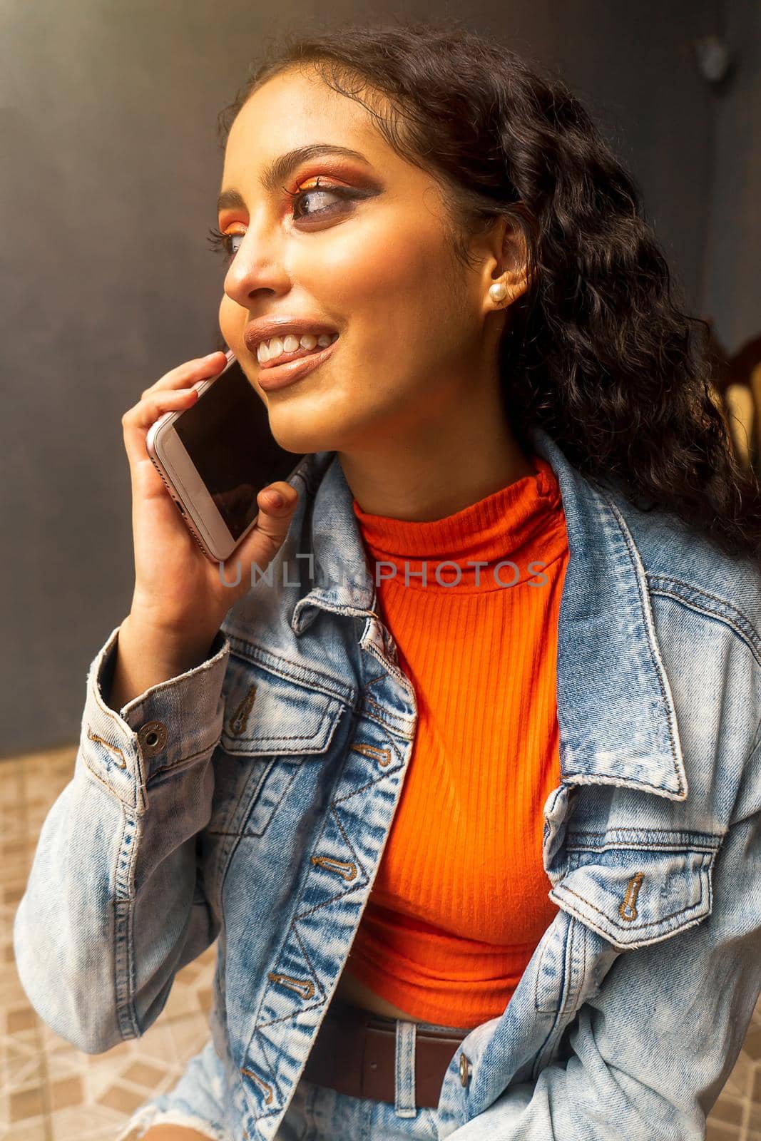 Latin teen gossiping on her cell phone making a phone call indoors at home.