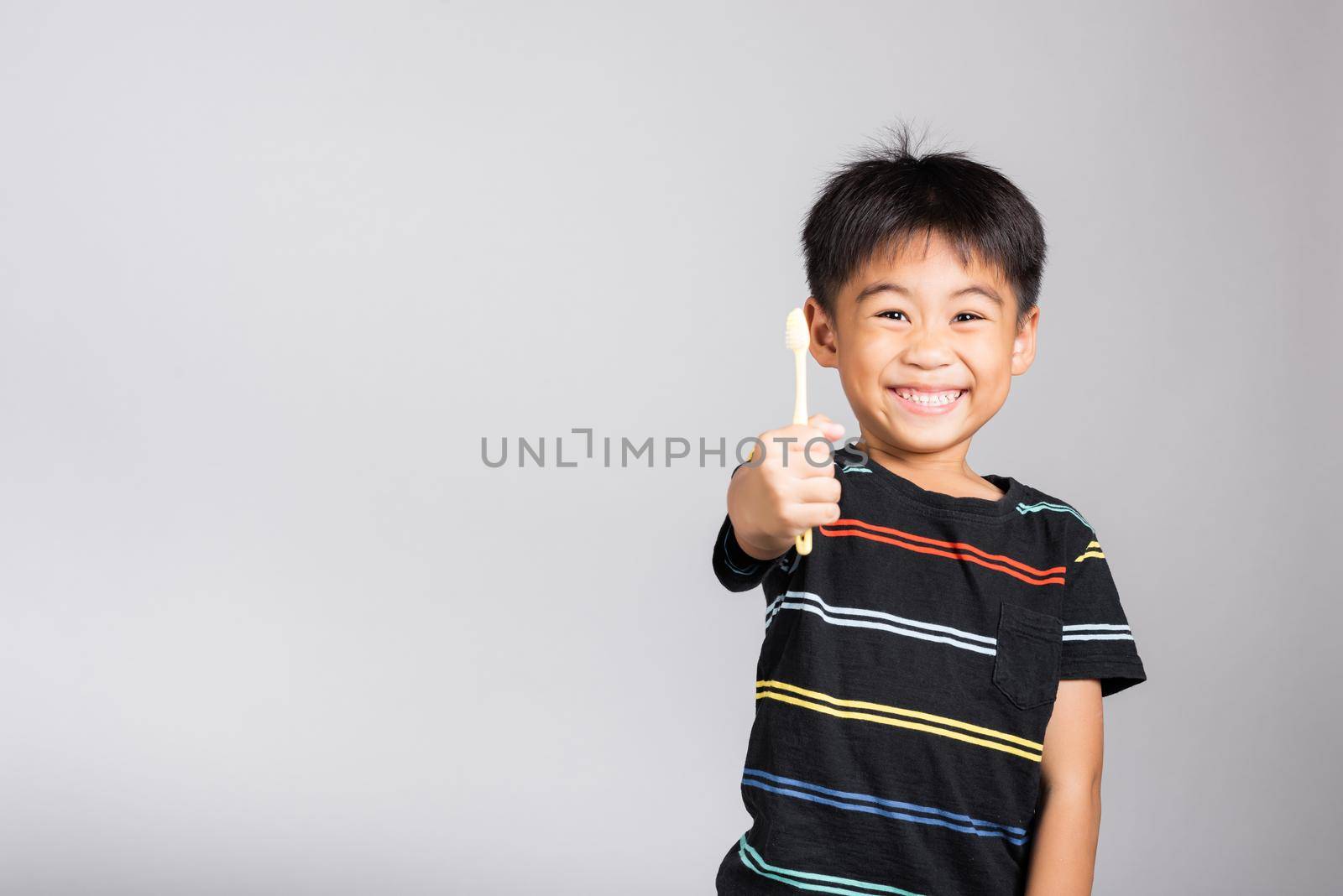 Little cute kid boy 5-6 years old show brush teeth and smile in studio shot isolated on white background, happy Asian children holding toothbrush in mouth by himself, Dental hygiene healthy concept