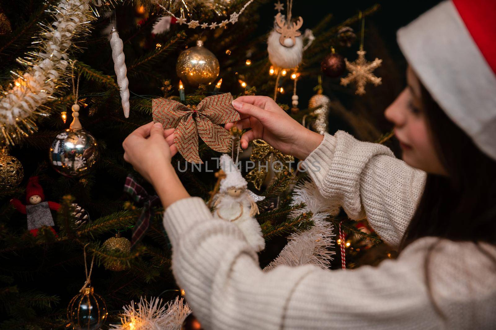 A young brunette girl decorates a Christmas tree according to Polish tradition. An annual important Christmas ritual among Christians.