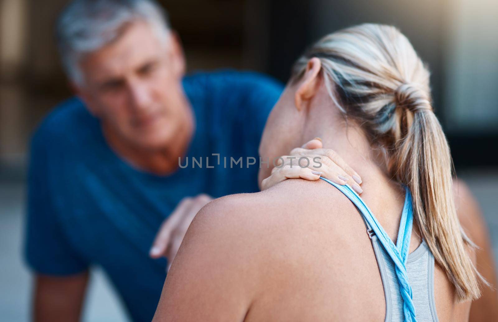 Shot of a mature woman holding her neck in pain after an intense workout session with her husband.