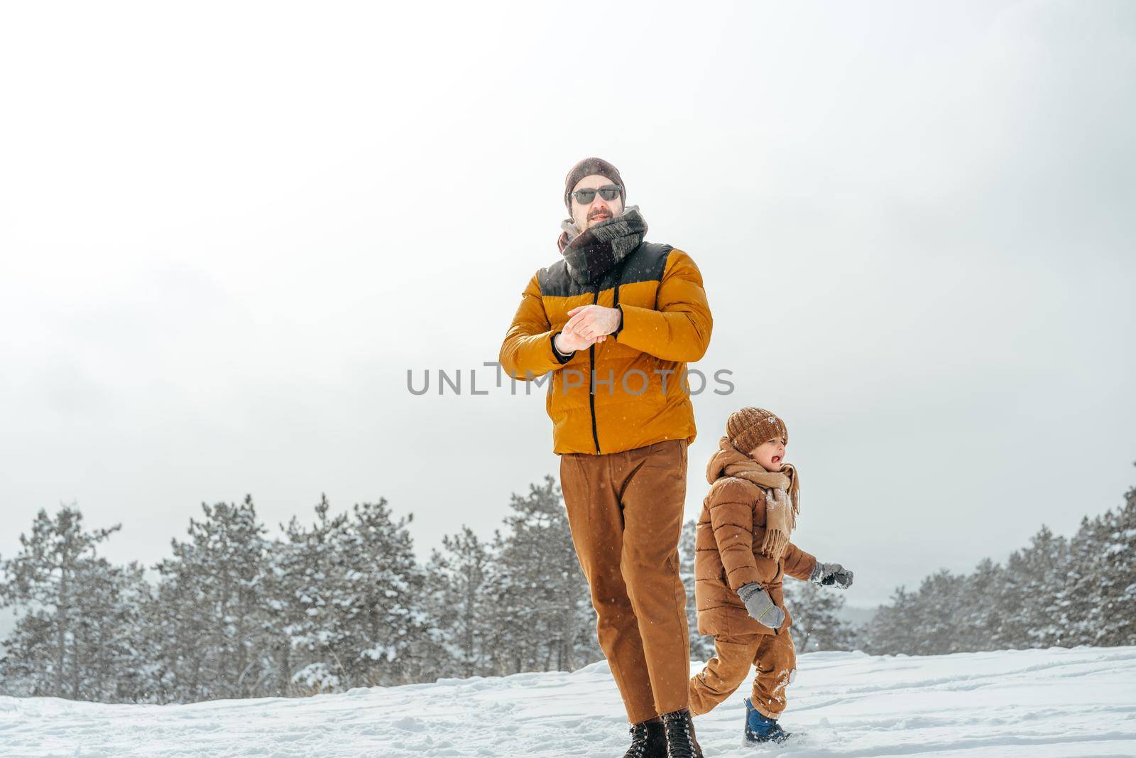 Father and son playing in the park on winter snowy day