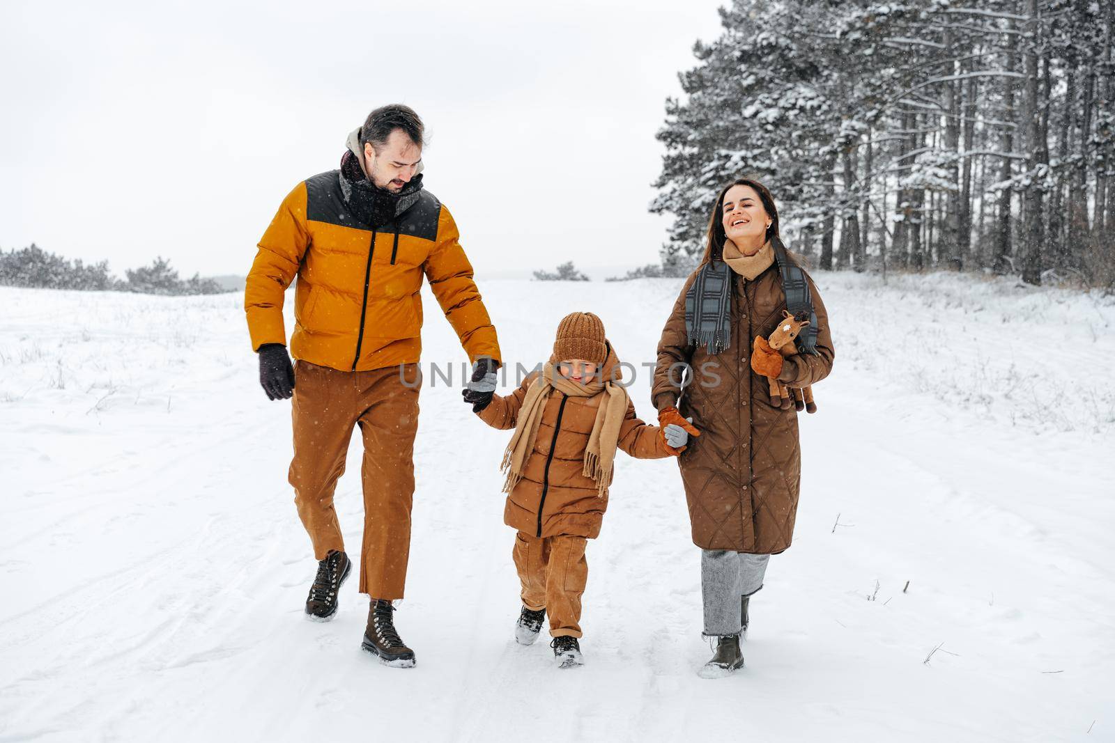 Happy family having a walk in winter outdoors in snow forest by Fabrikasimf