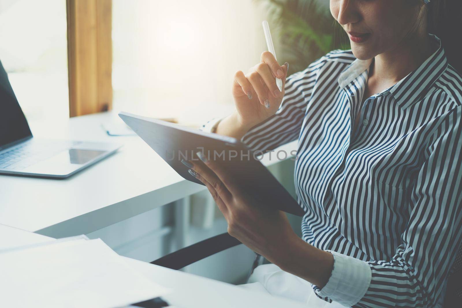 Business woman hand holding pencil looking at bank savings account application on digital tablet. account or saving money or insurance concept