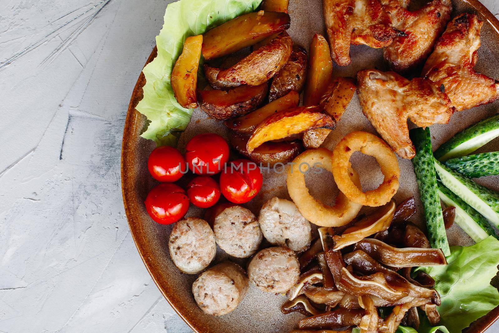 Clay plate full of delicious appetizers standing on white surface. by StudioLucky