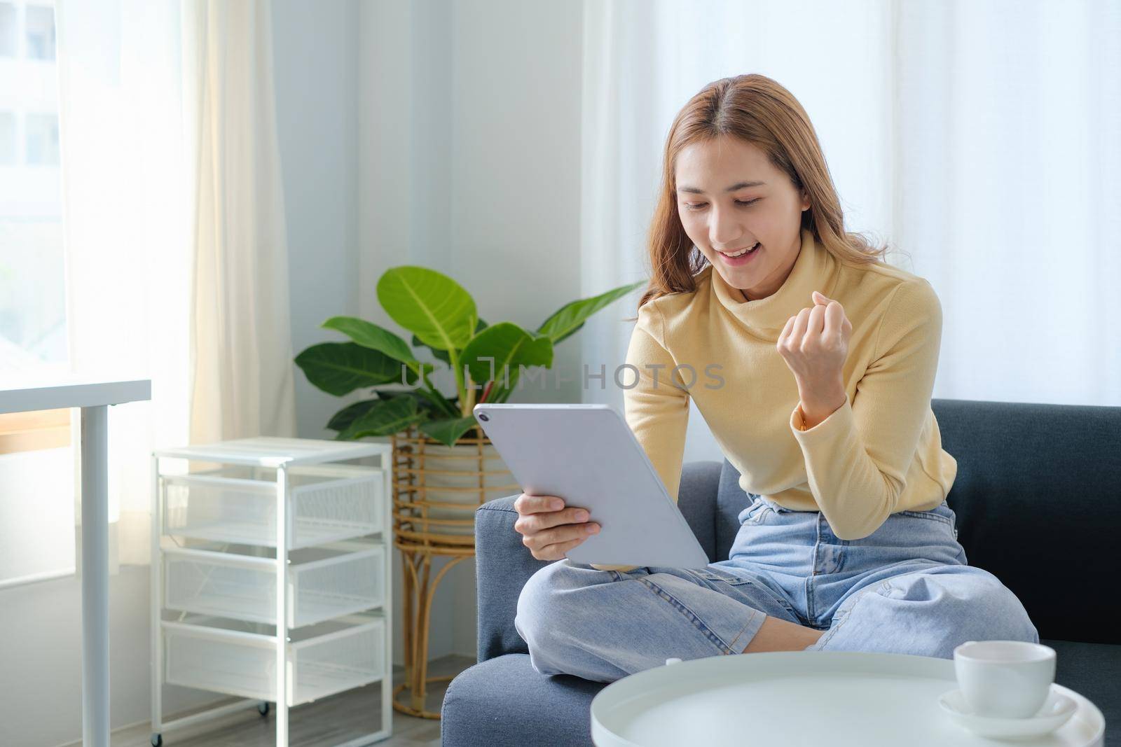 Woman enjoy with content social media application on digital tablet sitting on sofa at home