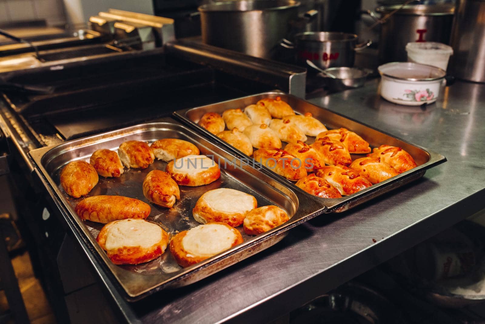 Delicious fresh baked flavored buns set made of sweet dough laying on big metallic dish standing in bakery kitchen. Looking mouthwatering, tasty. Laying near warm buns with cottage cheese feeling.