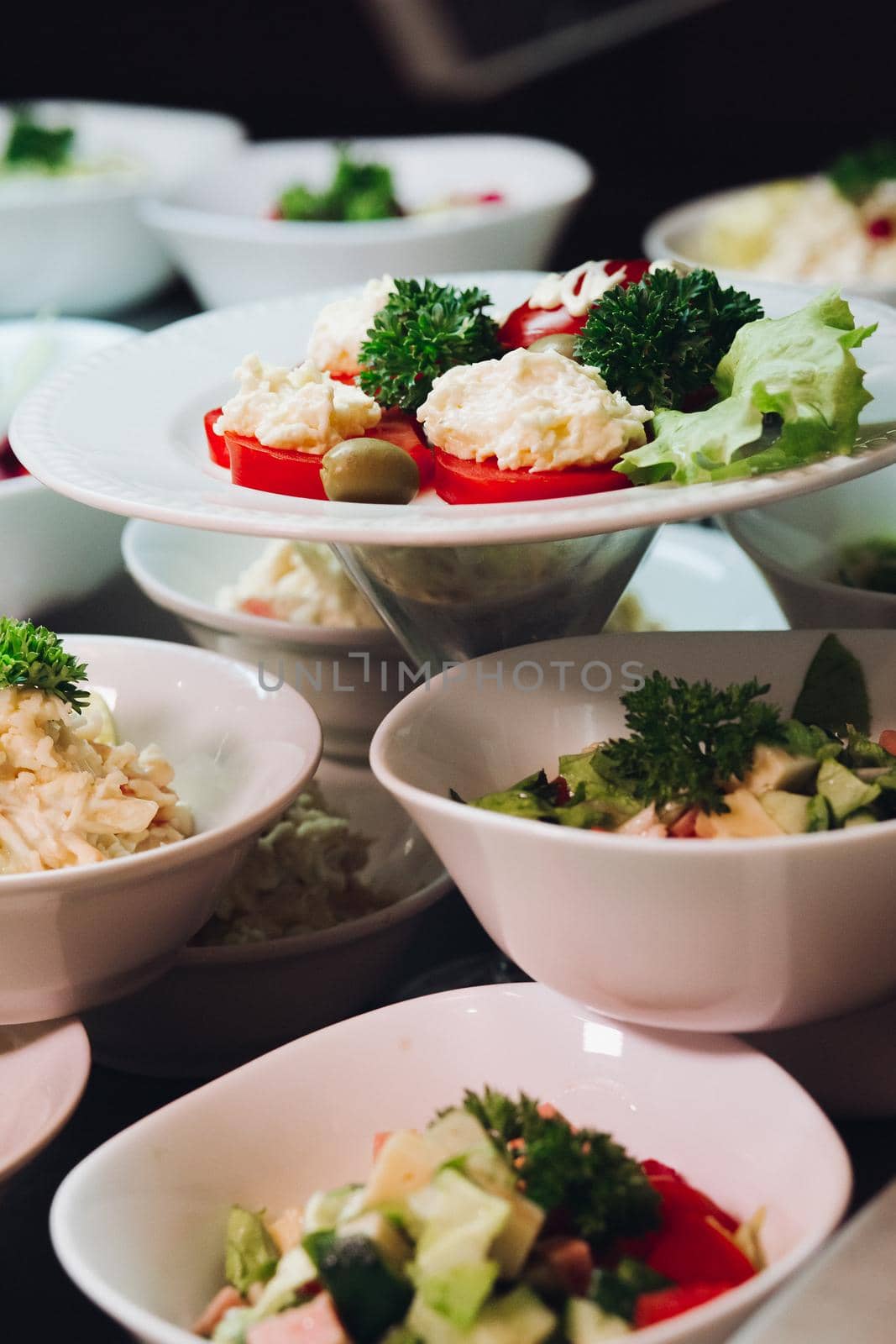 View of many round plates with tasty vegetables dish of salads with tomato, onion, zucchini, tomato and herbs. Big delicious for dinner in restaurant.