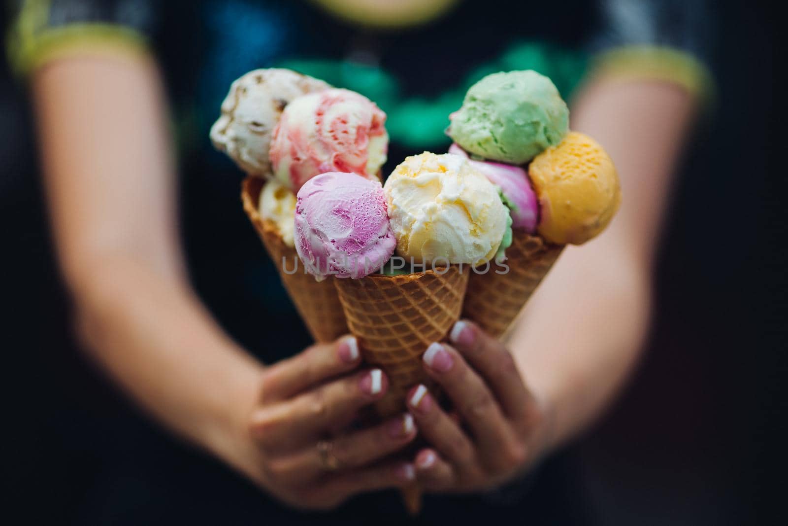 Close up of woman holding in hands and showing at camera many colorful ice cream. by StudioLucky