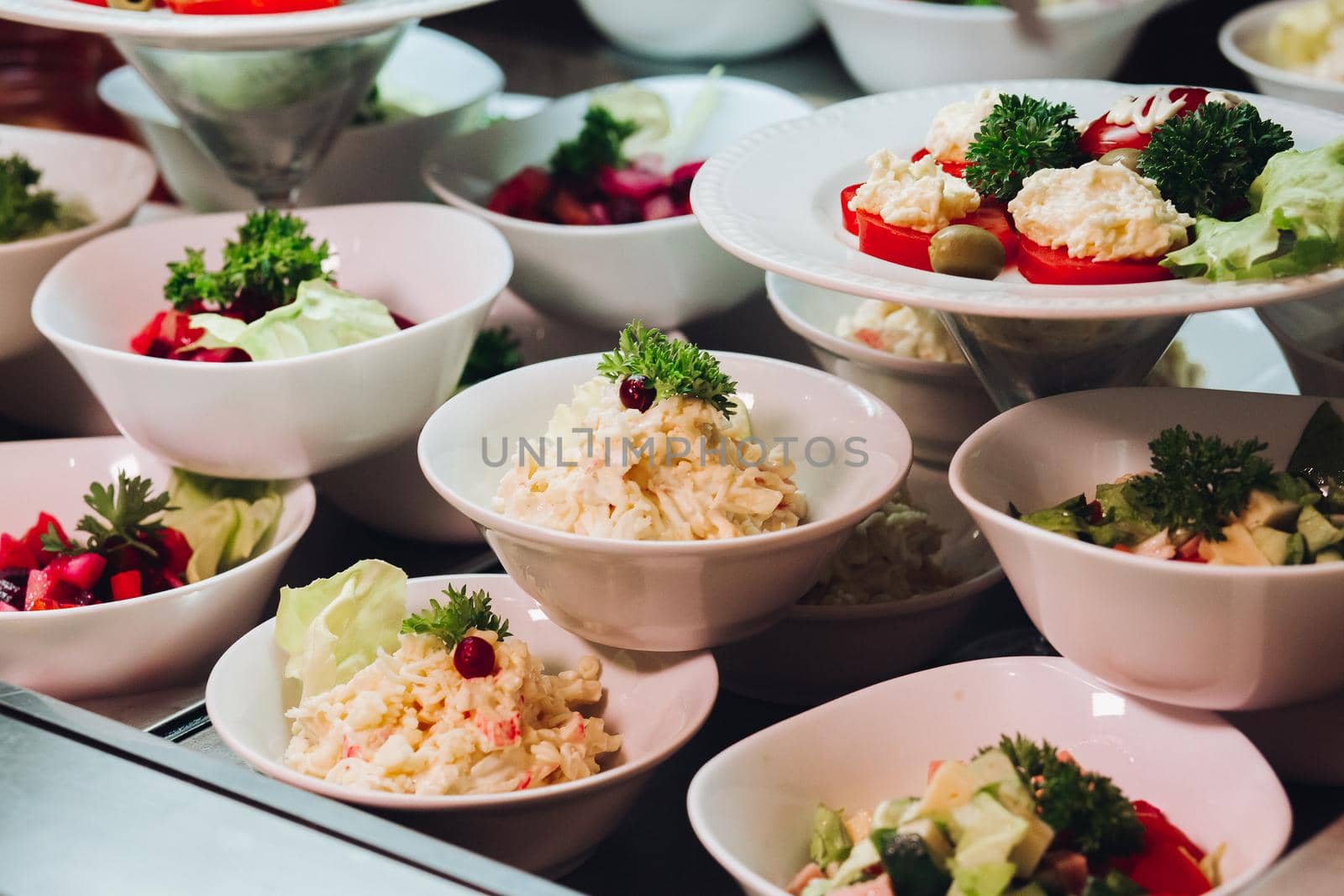 Many round plates with tasty vegetables dish of salads in restaurant. by StudioLucky