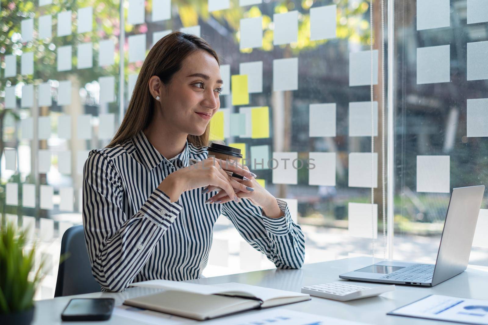 Happy asian Accountant sitting and holding coffee at office