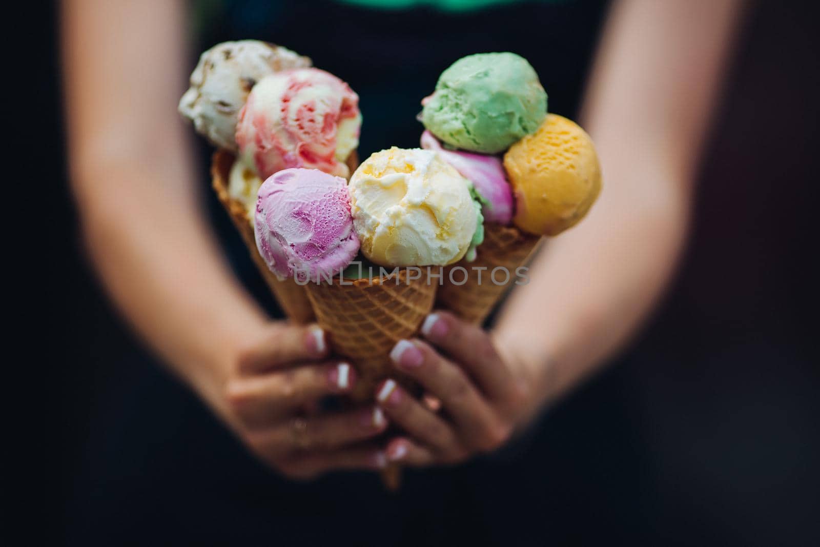 Close up of woman holding in hands and showing at camera many colorful ice cream, tasty, sweet, mouthwatering, perfect for summer heat. Girl with pretty nails eating sweet food.