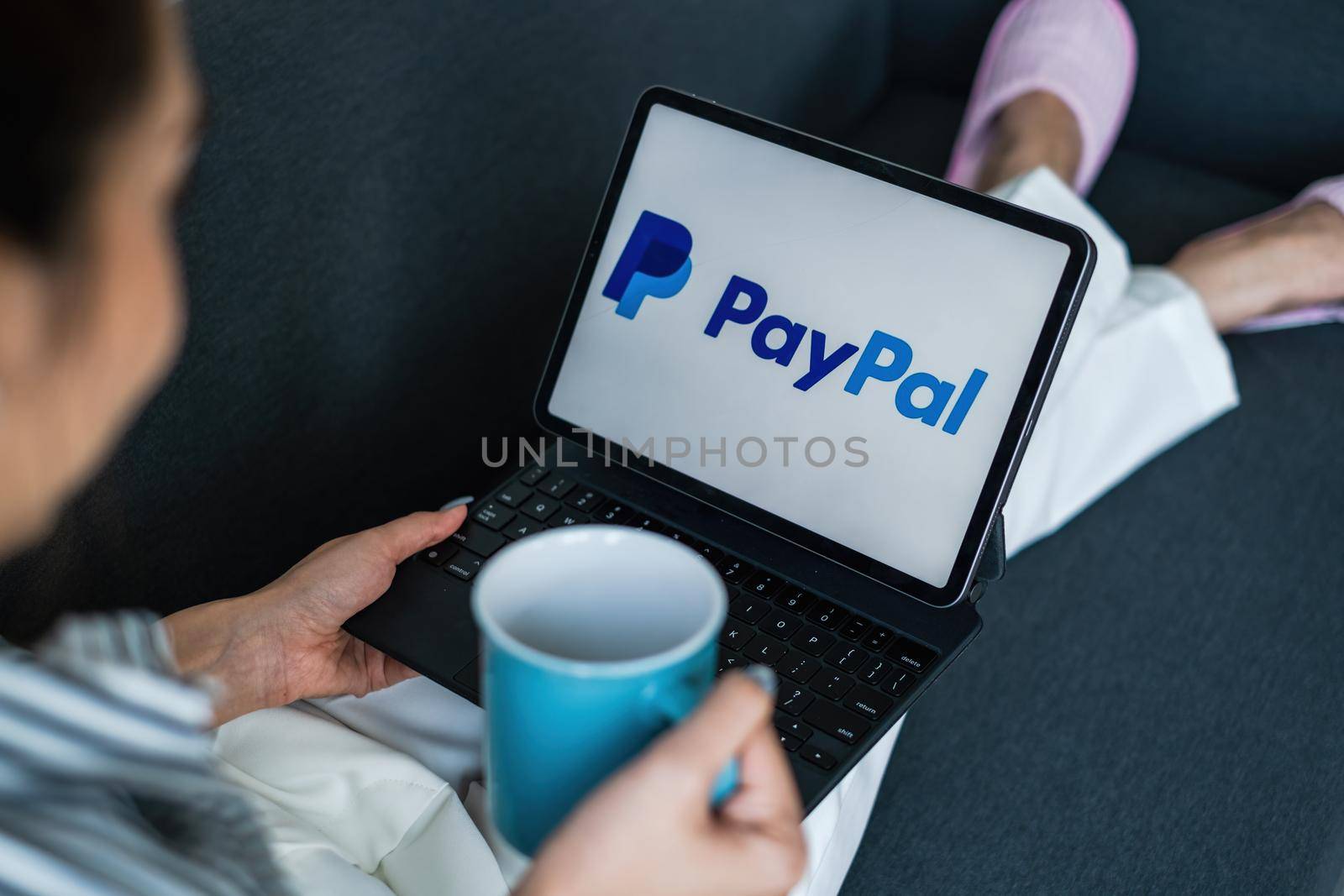 CHIANG MAI, THAILAND - MAR 18 2021 : Woman using Ipad with paypal logo on screen. PayPal is a worldwide online payment system and one of the most popular ways of making payment on the Internet