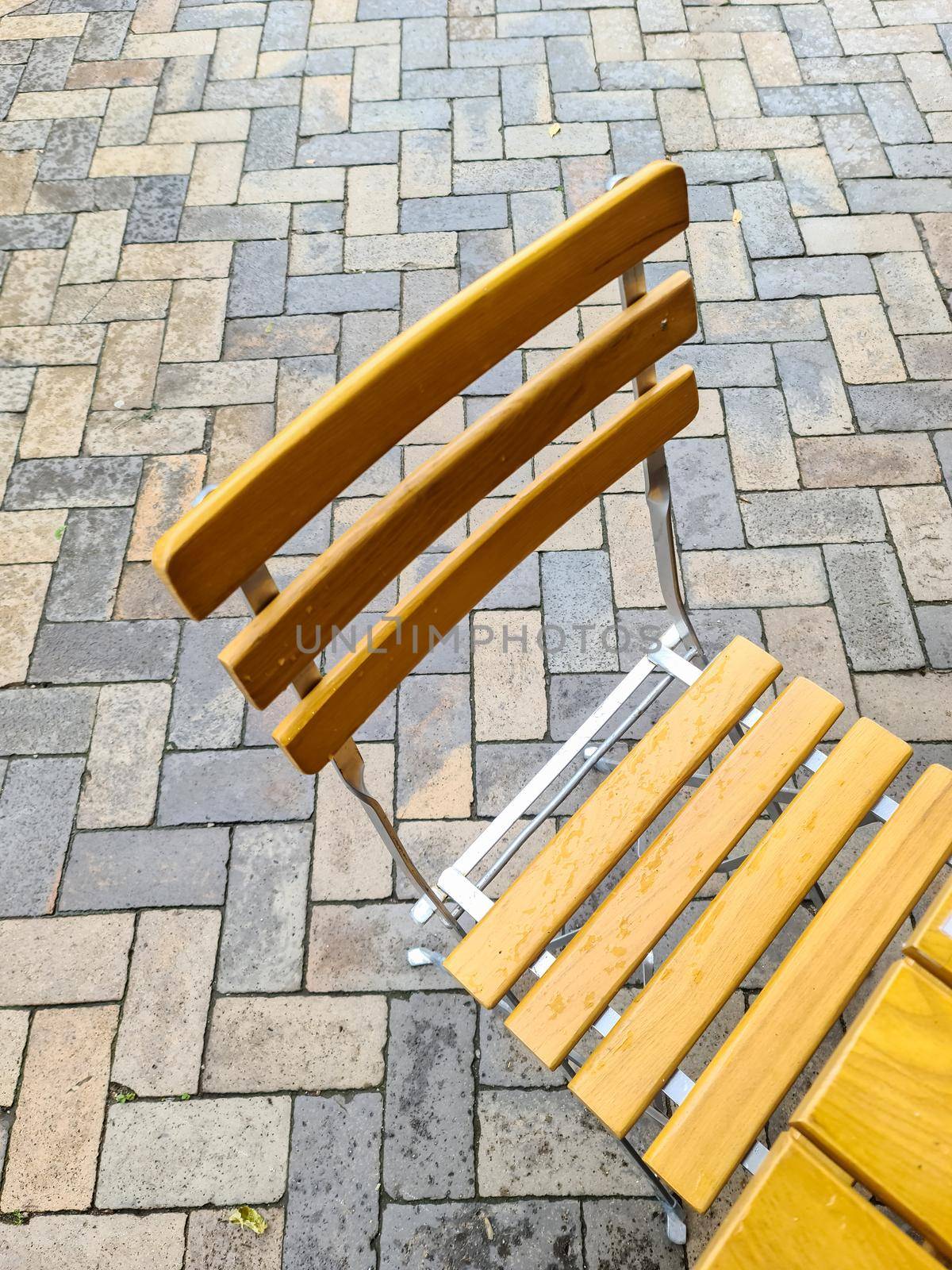 Wooden chairs on a cobblestone sideway in front of a restaurant. High angle view.