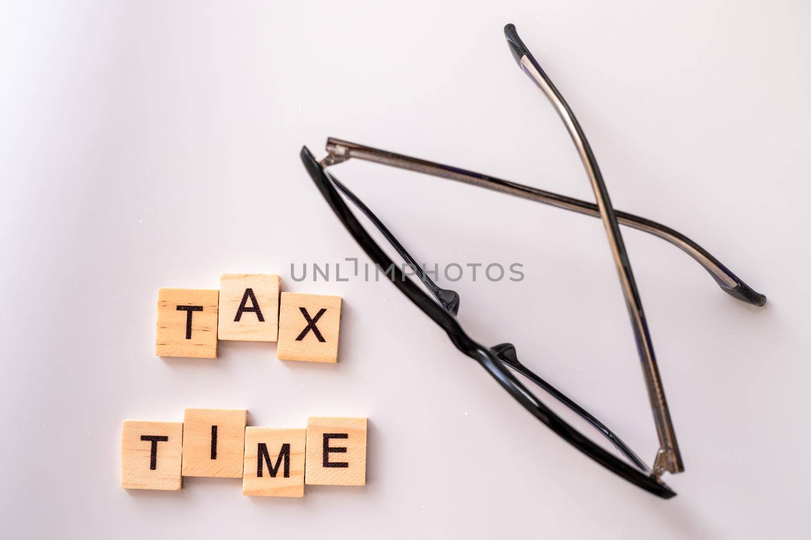 Close-up of alarm clock next to tax time concept on chalkboard by Matiunina