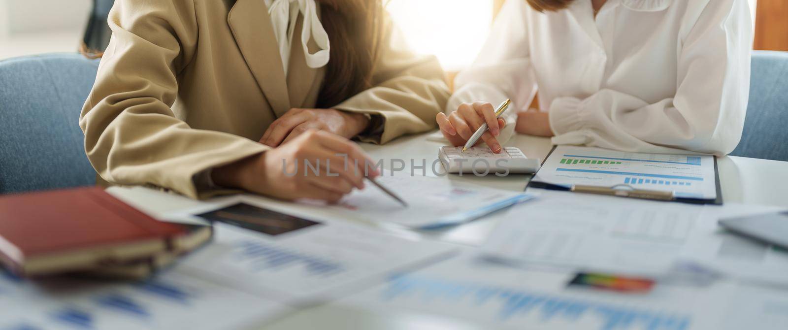 Crop image of business partnership coworkers using a calculator analysis graph company financial budget report and cost work progress and planning on workplace. by nateemee