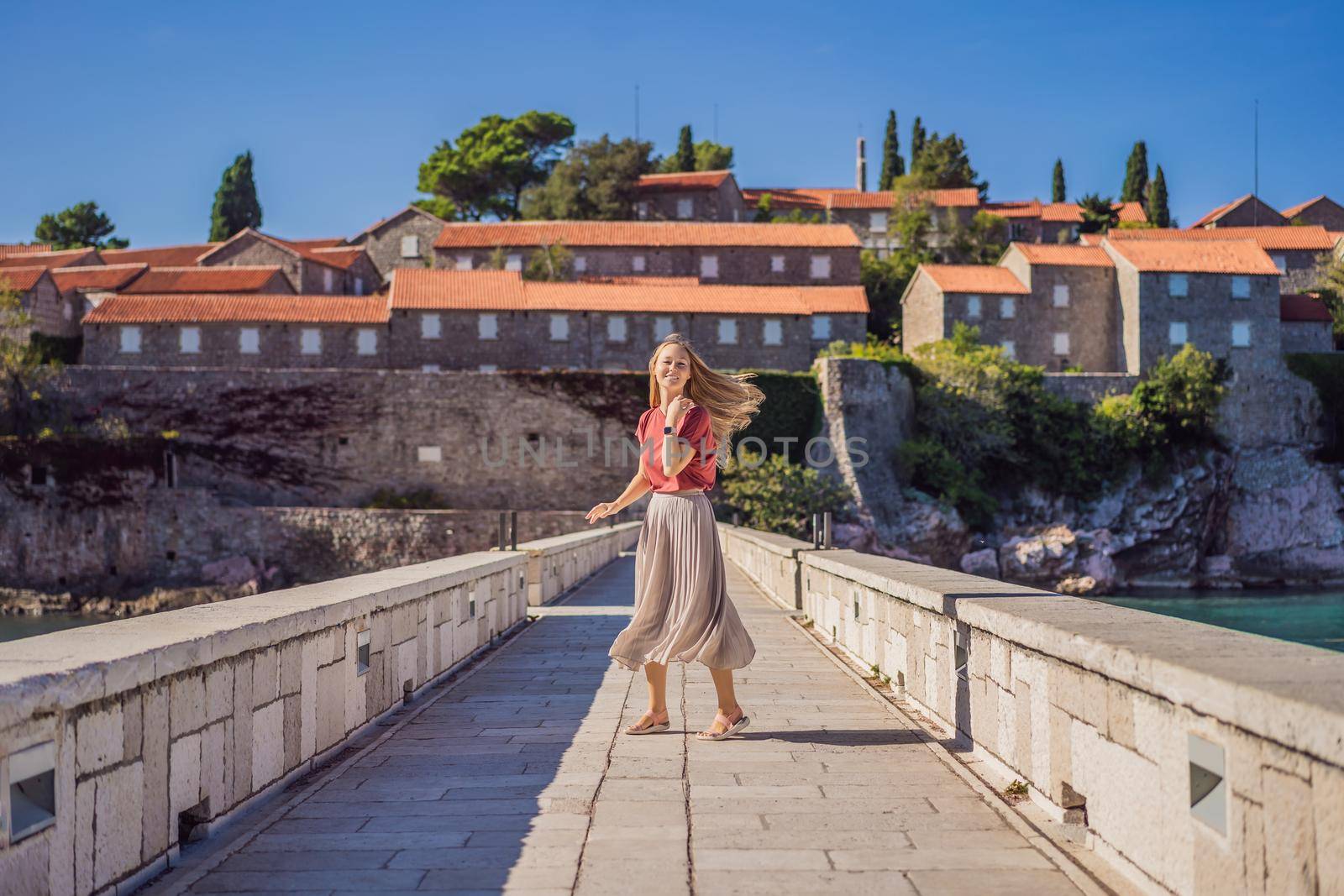 Woman tourist on background of beautiful view of the island of St. Stephen, Sveti Stefan on the Budva Riviera, Budva, Montenegro. Travel to Montenegro concept.