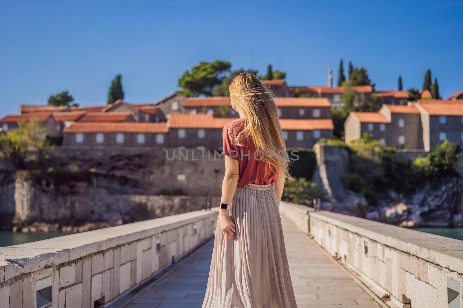 Woman tourist on background of beautiful view of the island of St. Stephen, Sveti Stefan on the Budva Riviera, Budva, Montenegro. Travel to Montenegro concept.