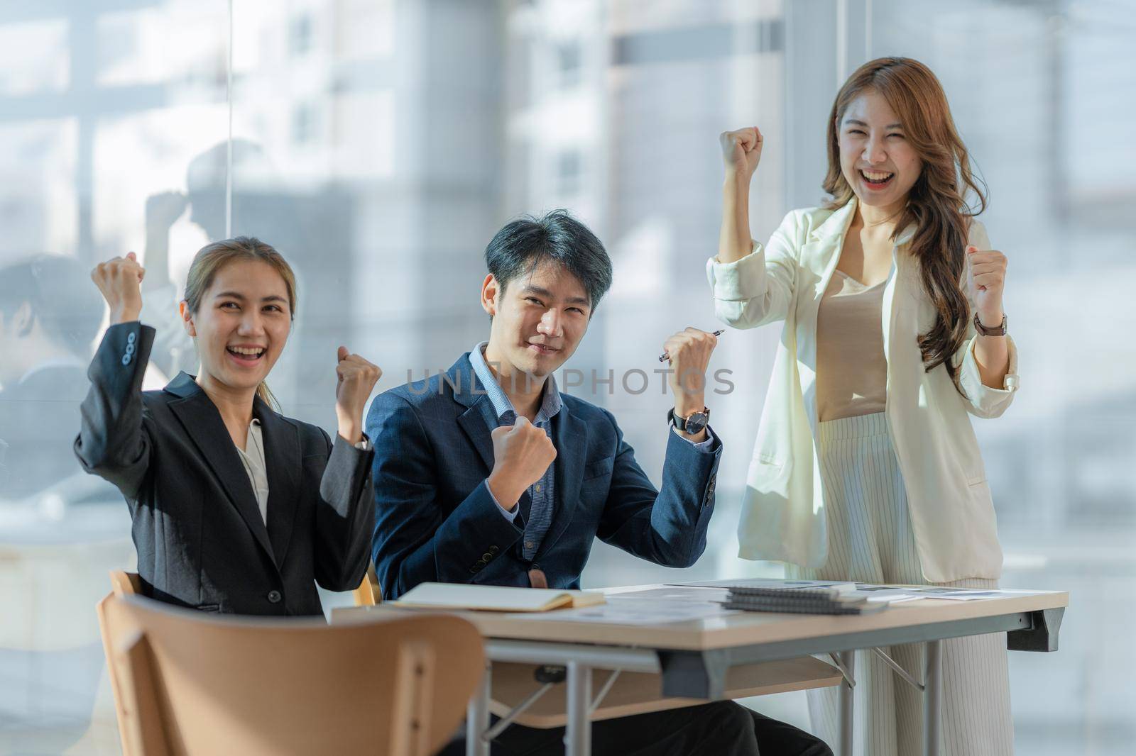 Asian business people give each other show hand of success symbol as they celebrate a successful team building project