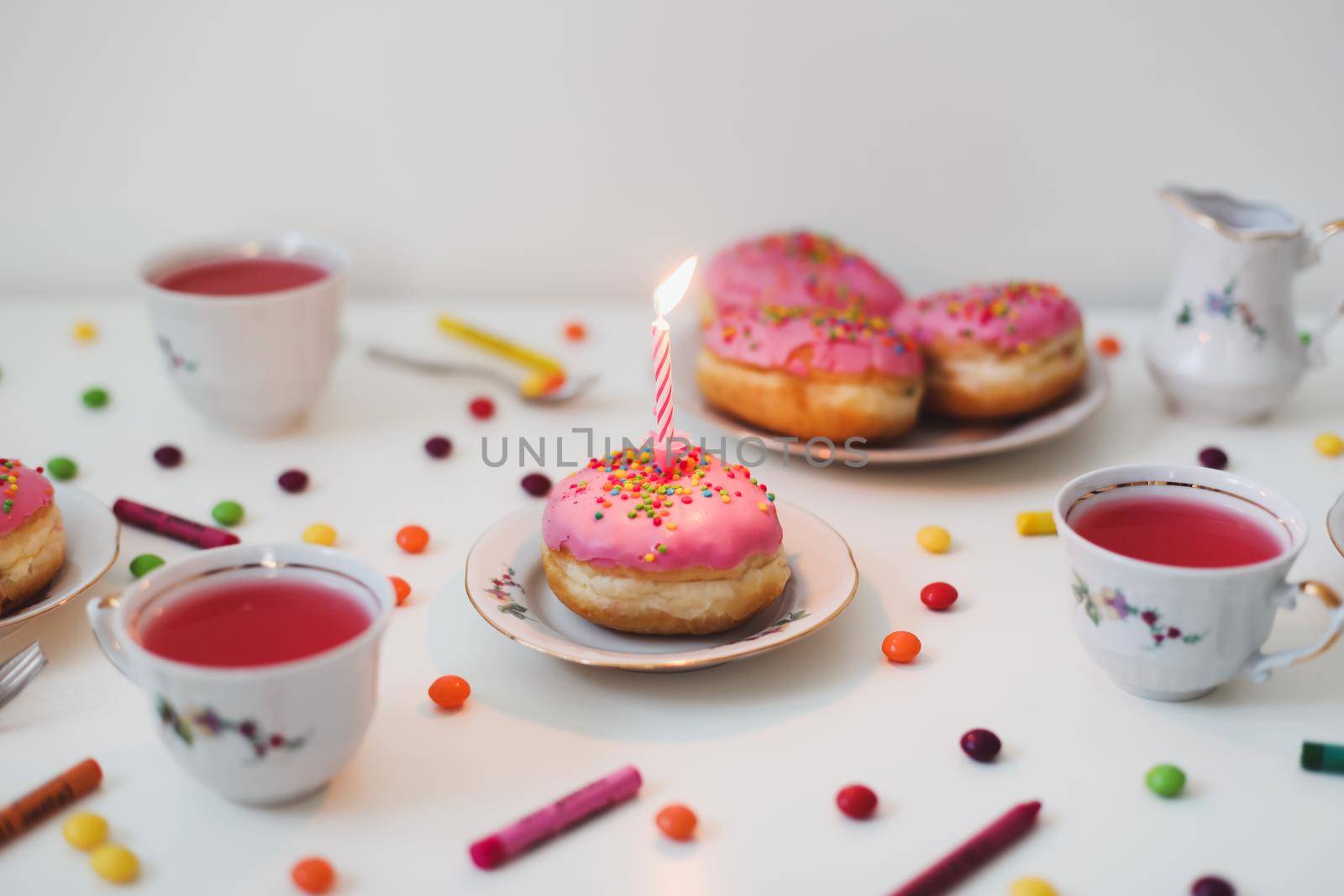 holiday, birthday party composition with colorful pink glazed donuts on white table, flatlay top view. 