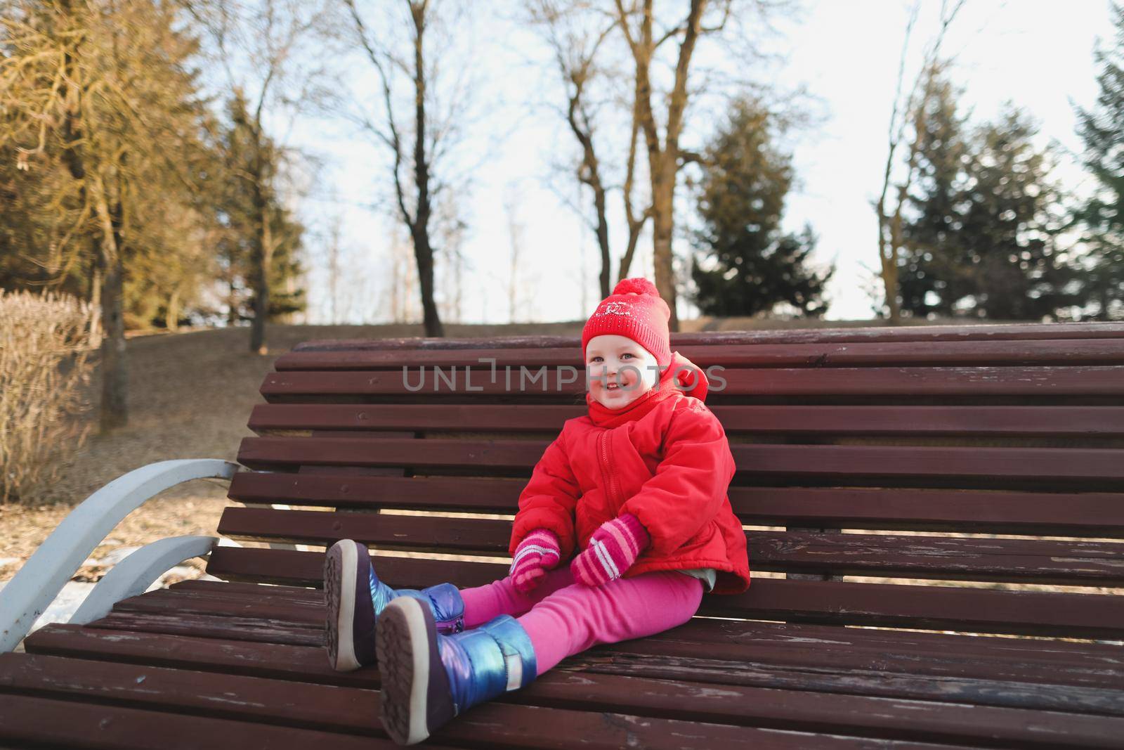 happy baby girl in boots and red jacket. funny cheerful toddler girl playing outdoors by paralisart