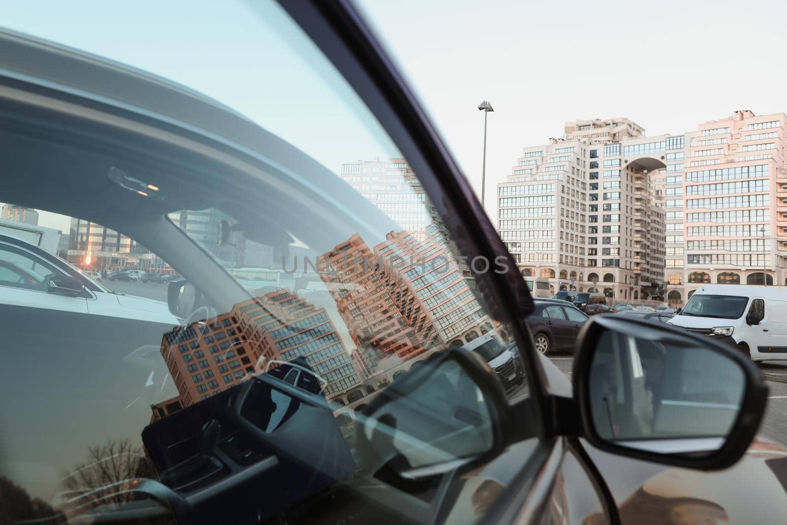 The urban landscape reflected in car mirror. Exteriors of typical modern apartment buildings against a blue sky with clouds by paralisart