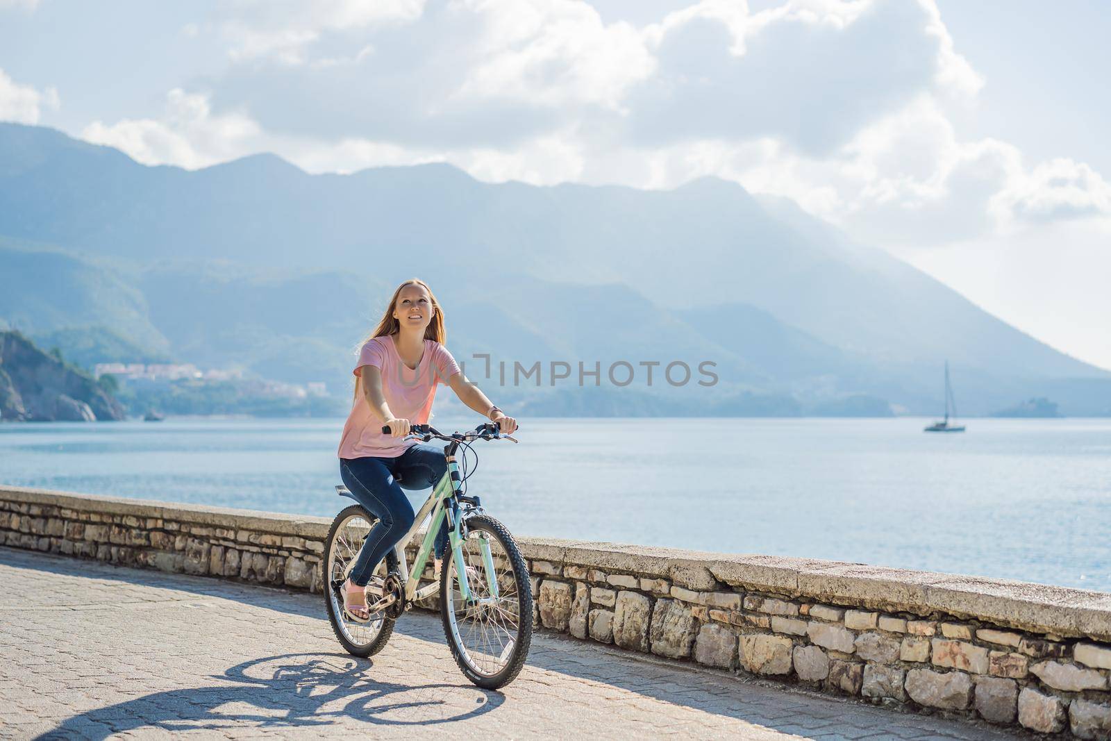 Woman tourist on a bicycle explores Budva in Montenegro. Cycling in Montenegro concept.