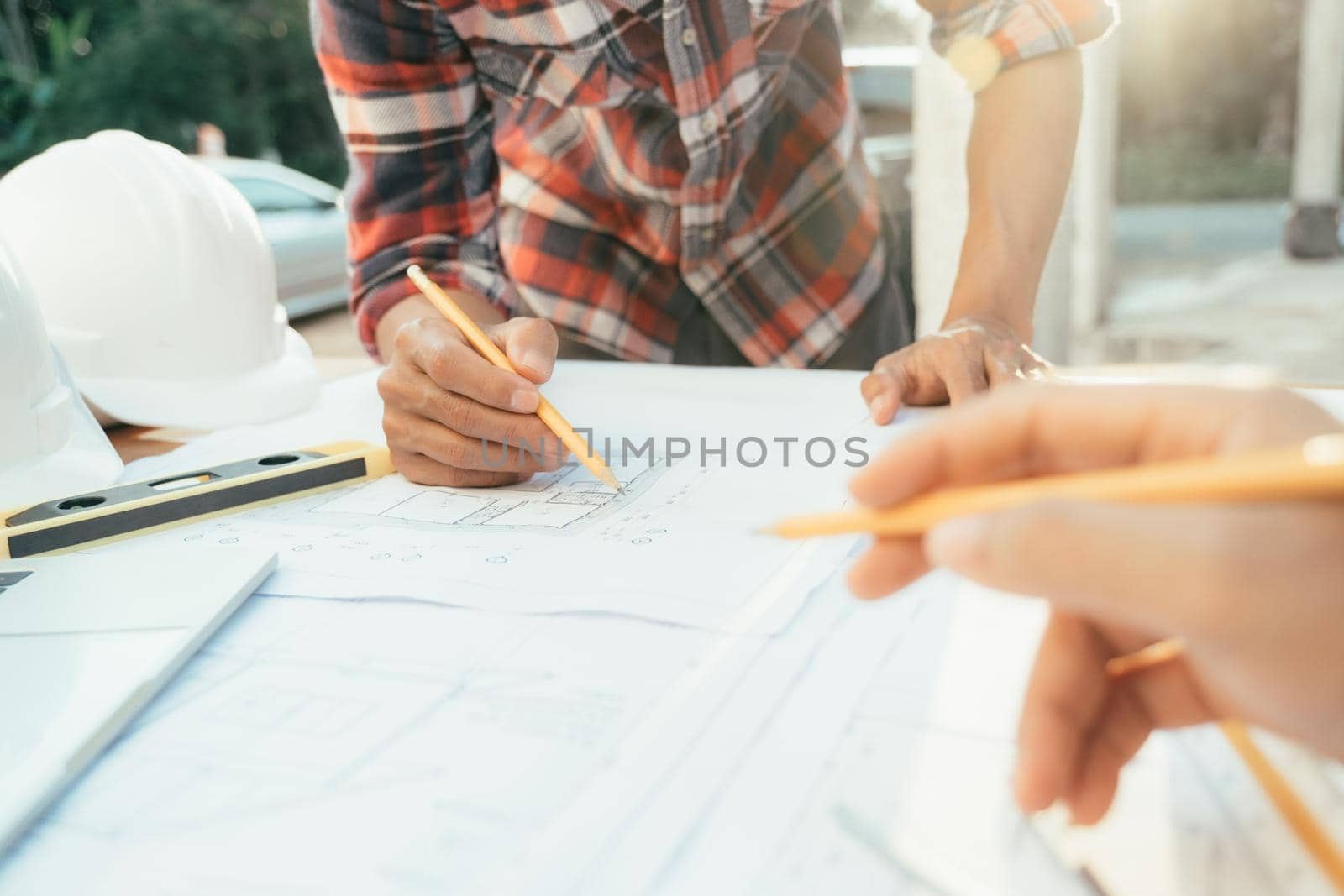 Hands of an architect and an engineer pointing at the architectural plan. they have a coordination meeting to make sure everything works
