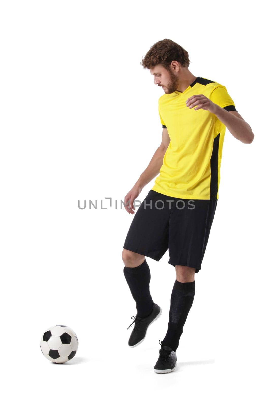Full length portrait of a soccer player kicking ball isolated on white background