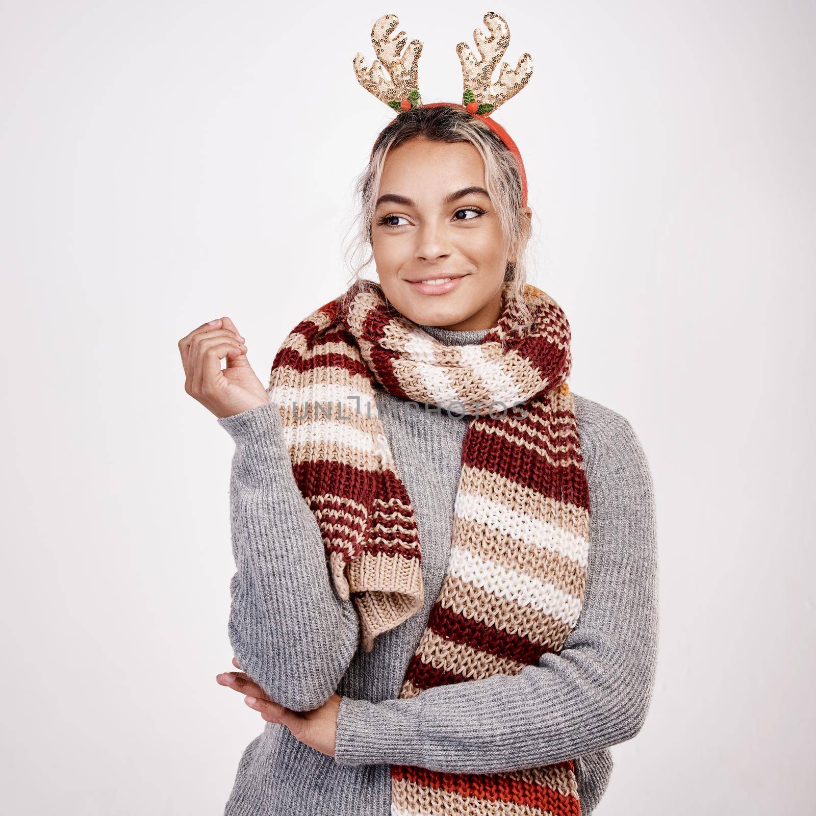 Studio shot of an attractive young woman looking thoughtful while dressed in Christmas-themed attire.