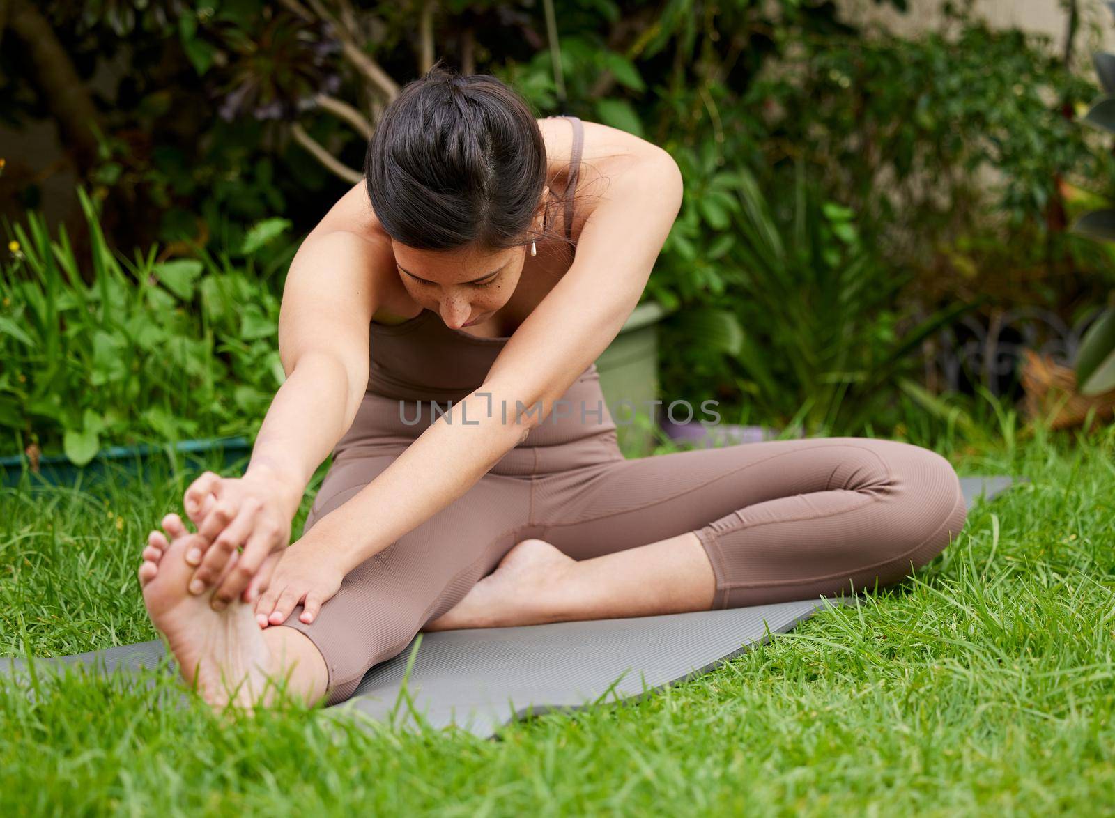 Regular movement is good for your body. Shot of a young woman stretching her legs while exercising outdoors. by YuriArcurs