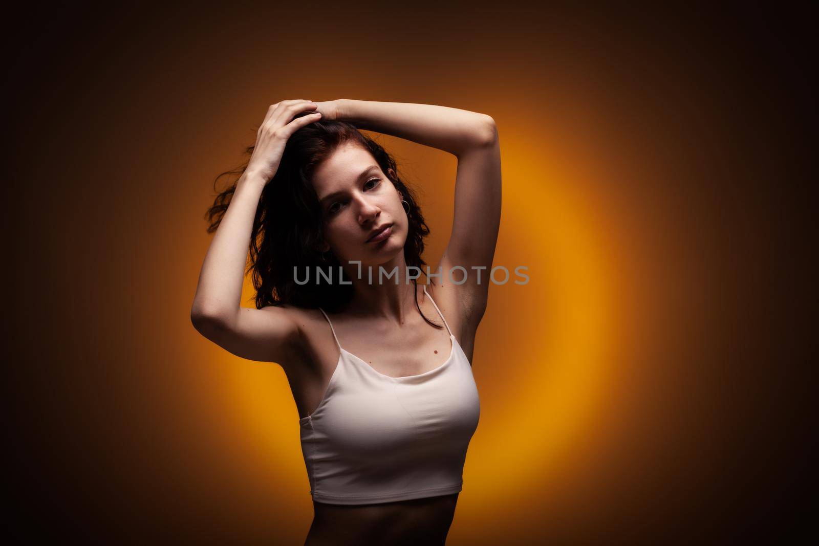 Beautiful teenage girl studio portrait on neon orange colored background.. by kokimk