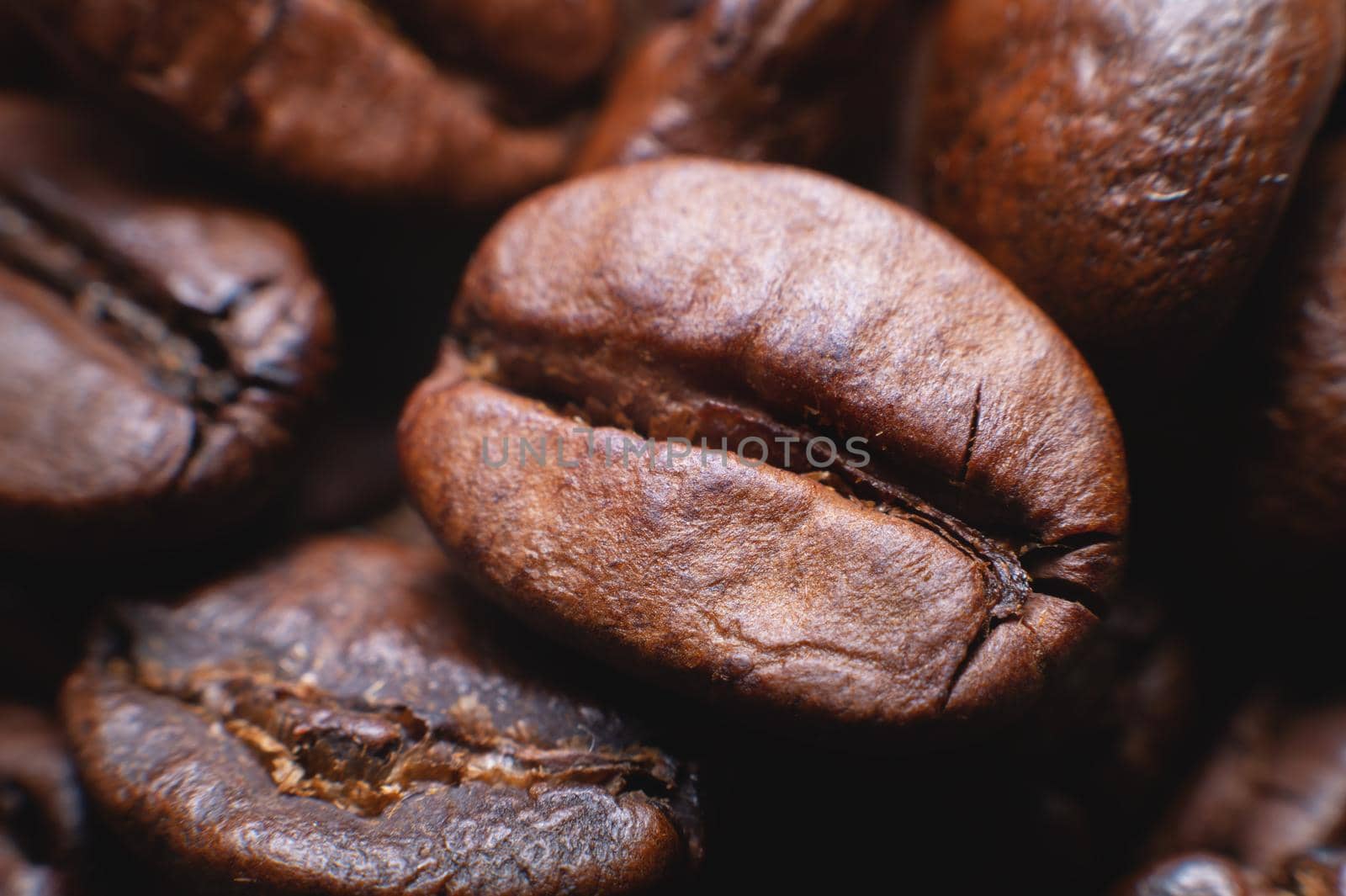 Close up extreme macro group of roasted brown or black coffee beans background in shallow depth of field. Enchanting coffee aroma.
