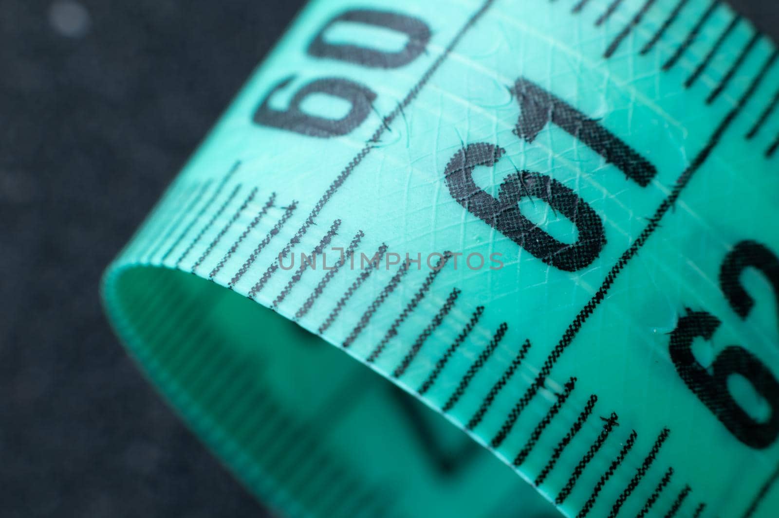 Close-up of rolled up tape measure on number 61. Slim waist and healthy weight concept by yanik88